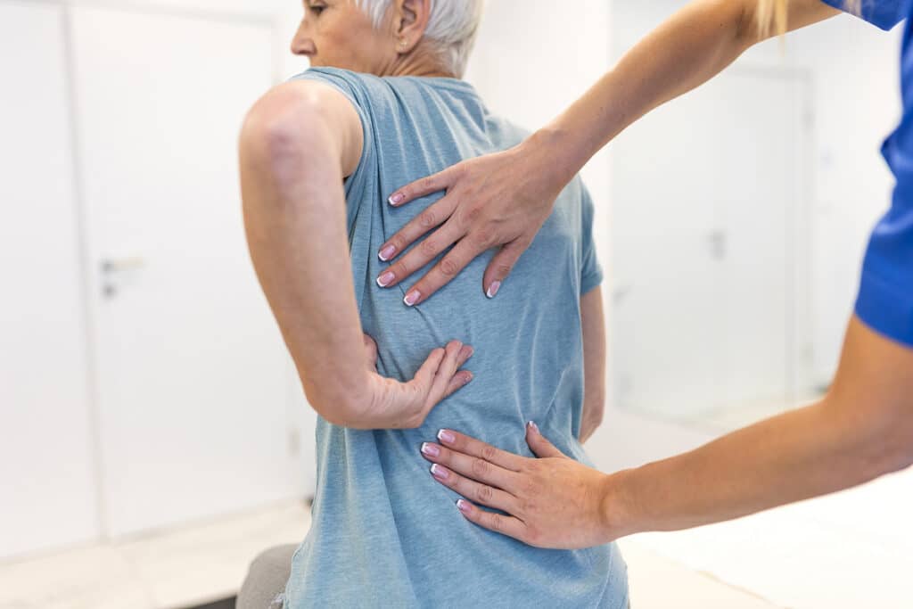 Healthcare provider examining patient's lower back and shoulder area for radiculopathy symptoms
